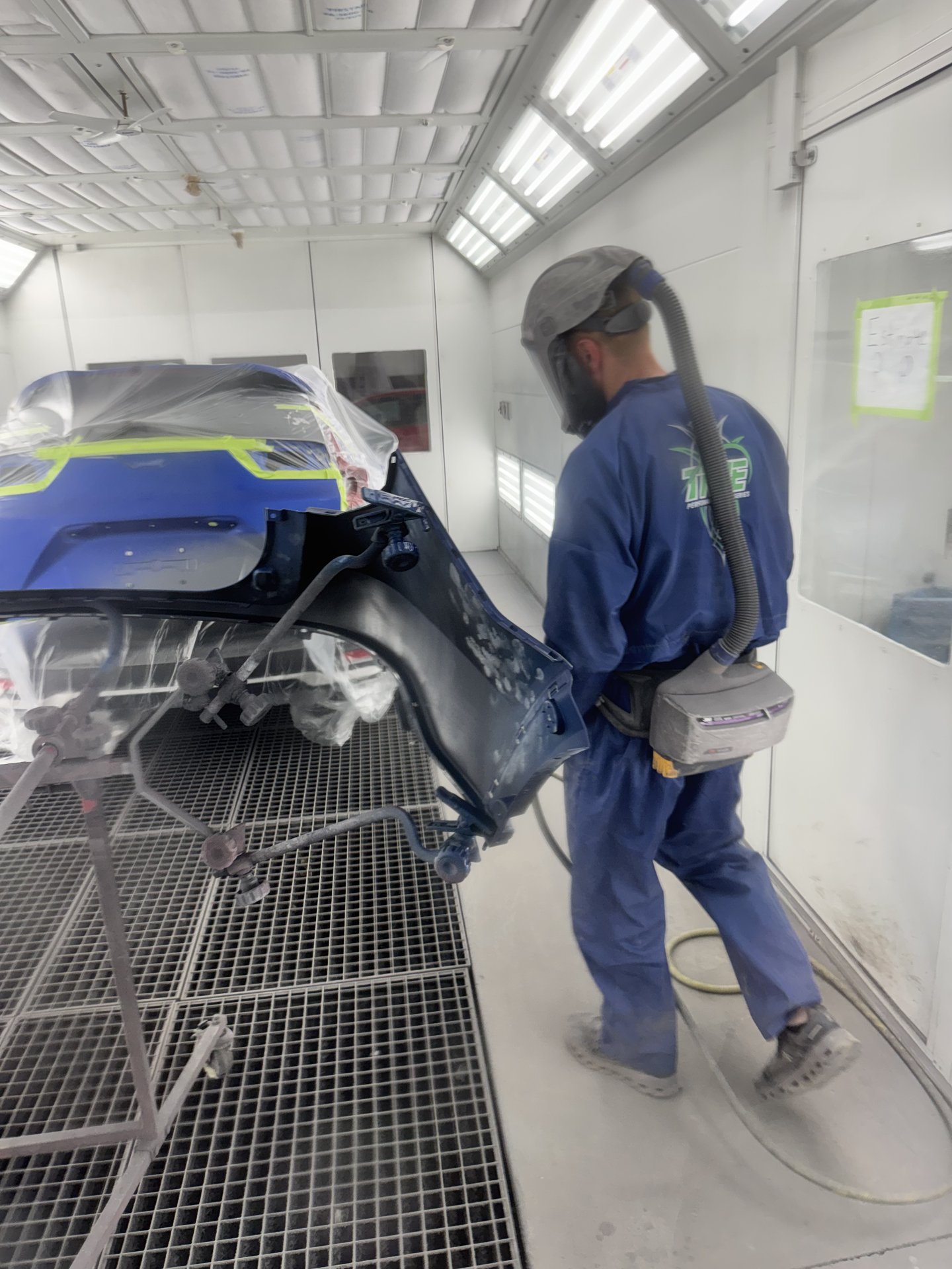 Paint technician applying Aegean Blue Metallic paint to a 2021 Honda CR-V inside the downdraft paint booth at Bob Rohrman Collision Repair Center in Lafayette, Indiana