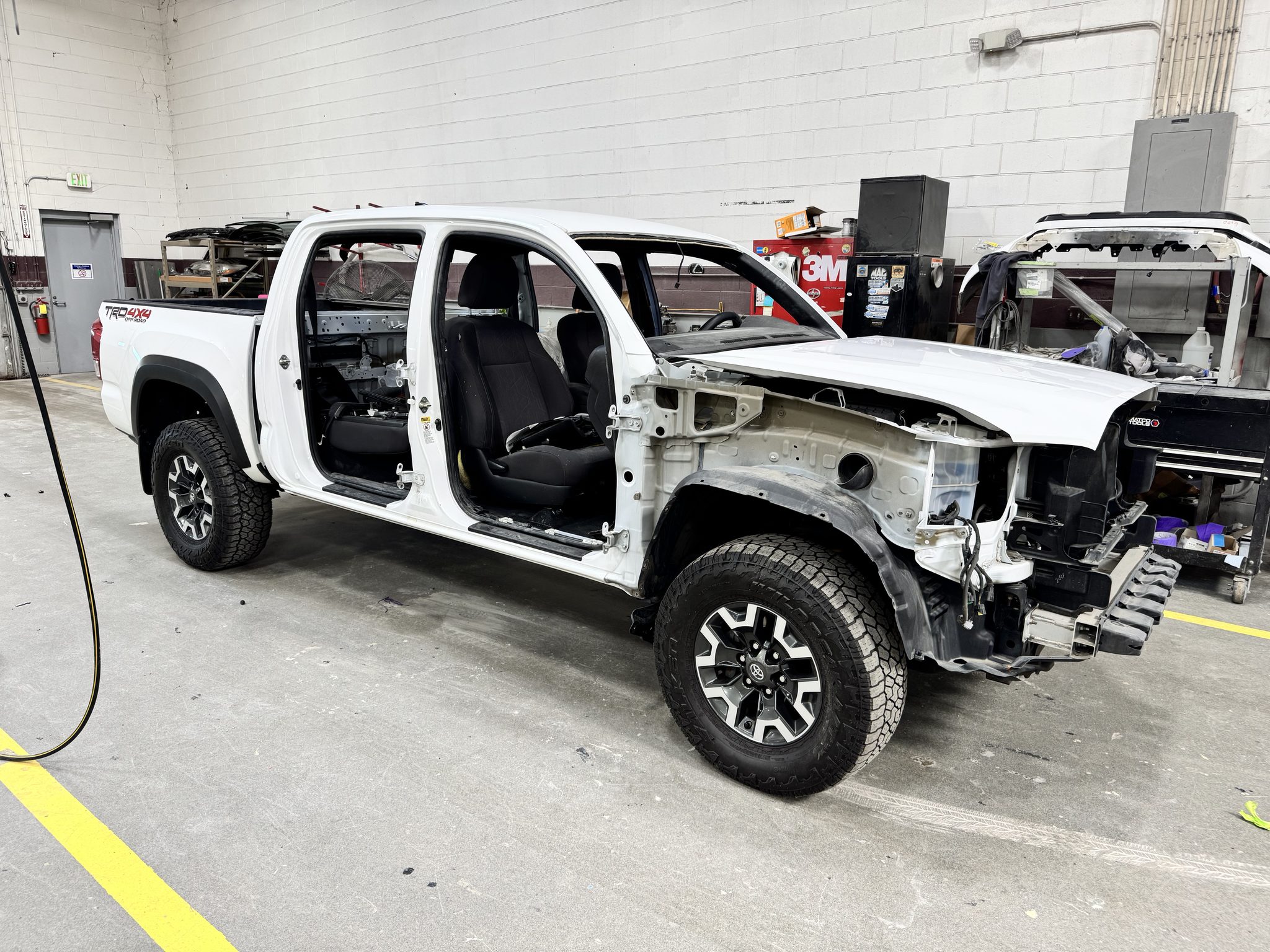 White 2020-2022 Toyota Tacoma TRD Off-Road with all four doors removed during a Toyota 23TE08 white paint refinish at Bob Rohrman Collision Repair Center in Lafayette, Indiana