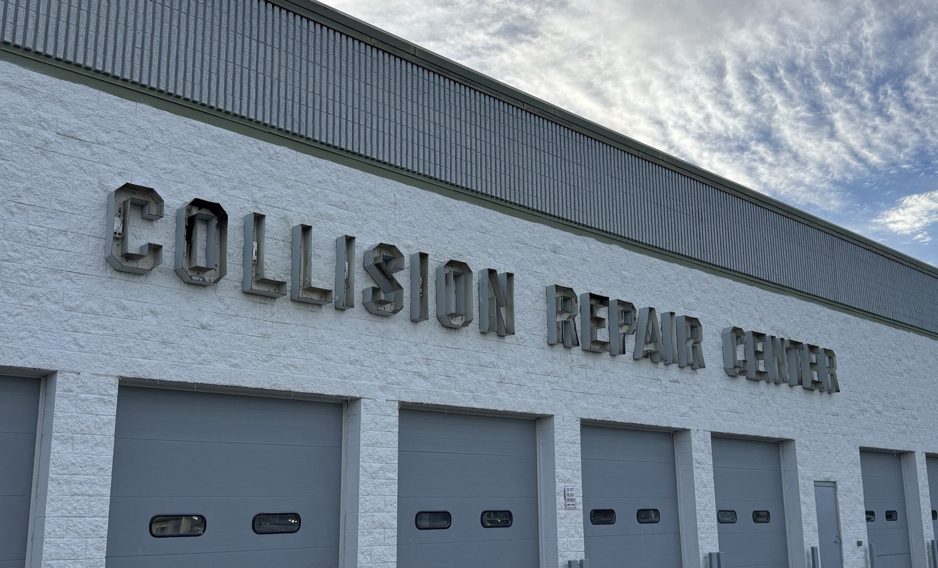 The old silver channel letters being removed from the Bob Rohrman Collision Repair Center building during the sign replacement installation
