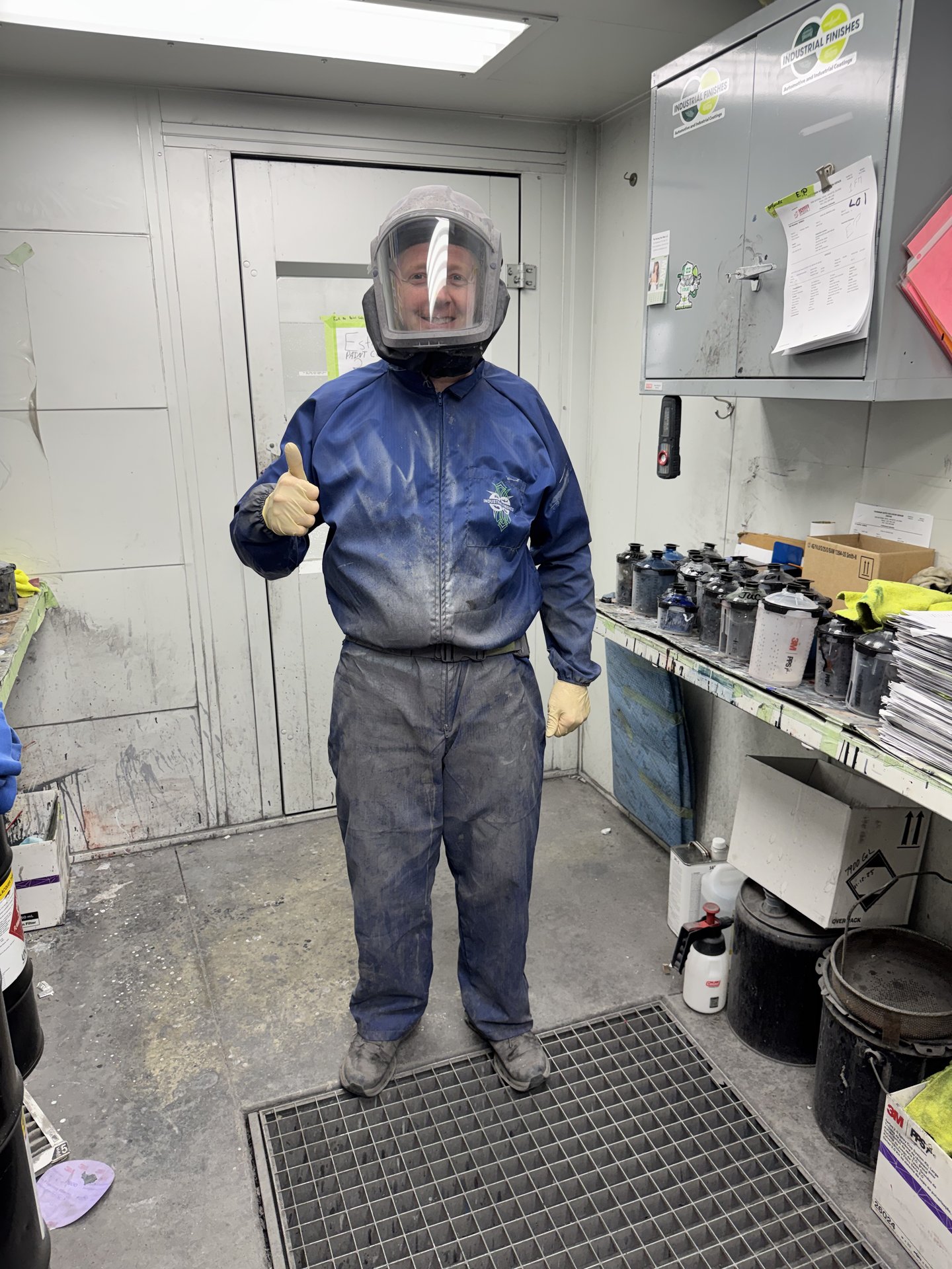 Paint technician at Bob Rohrman Collision Repair Center wearing full supplied-air respirator hood and paint suit, ready to enter the paint booth in Lafayette, Indiana